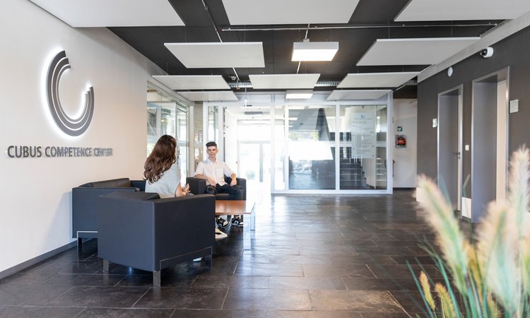 Personen sitzen im Foyer eines Bürogebäudes